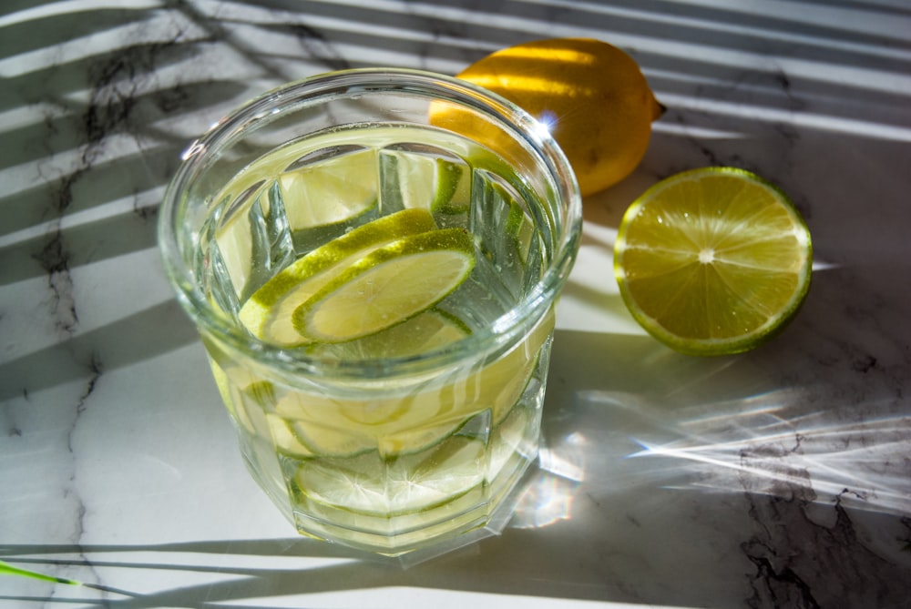 a glass of lemonade with limes and lemons