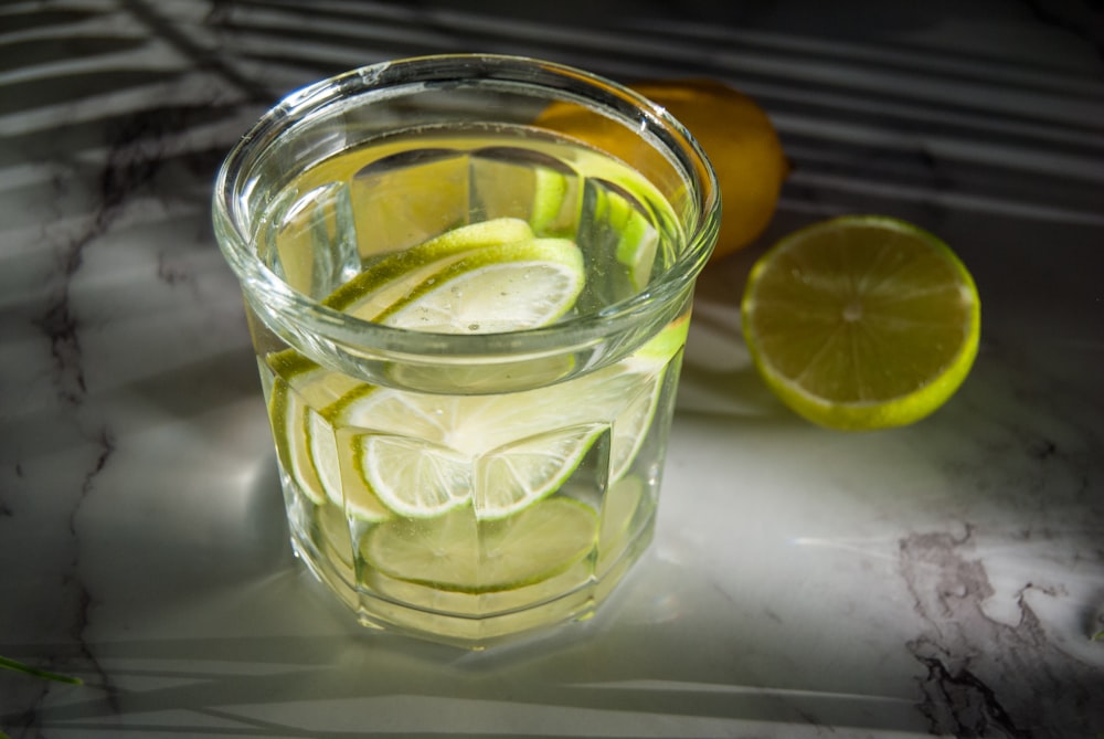a glass of lemonade with limes and a slice of lemon
