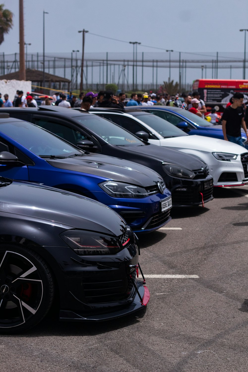 a group of cars parked in a parking lot with people in the background