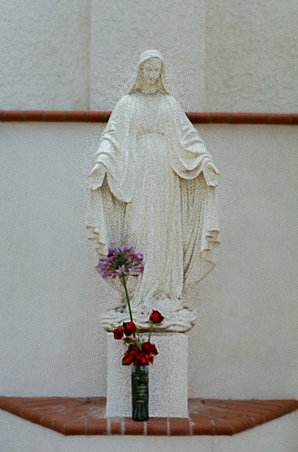a statue of a person in a white dress and a vase of flowers