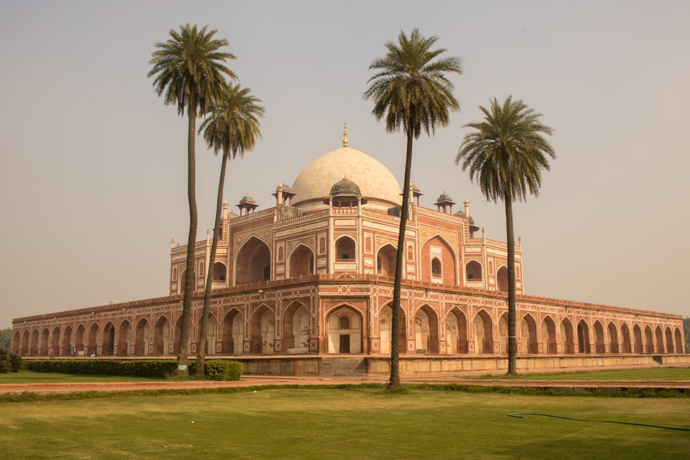a large building with palm trees with Humayun's Tomb in the background