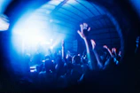 Crowd swaying in unison, bathed in deep blue and purple hues.
