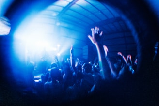 A dynamic shot of a live rock concert crowd with neon red lights cutting through the smoky air.