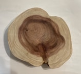 A cross-section of a tree trunk showing intricate growth rings, with variations of brown and beige colors indicating the wood's age and texture.