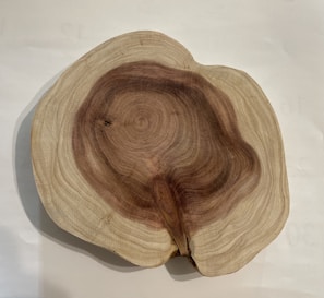 A cross-section of a tree trunk showing intricate growth rings, with variations of brown and beige colors indicating the wood's age and texture.
