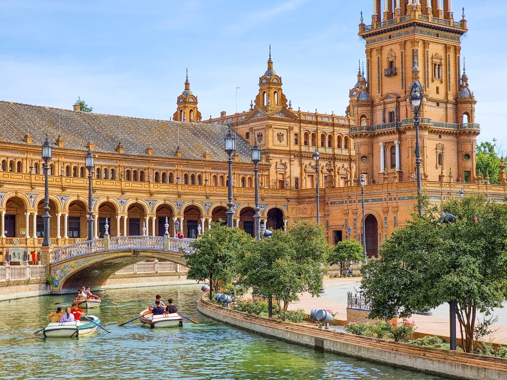 a group of people in a boat in a river in front of a large building