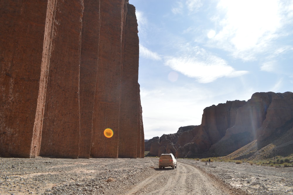Ein Auto fährt auf einem Feldweg zwischen großen Felsen