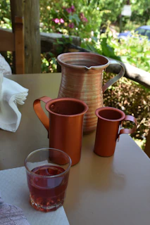 A set of polished copper pitchers arranged on a rustic wooden dining table