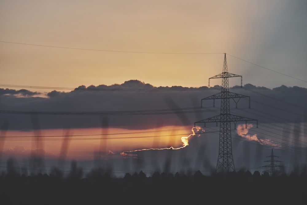 a power line tower with a sunset in the background