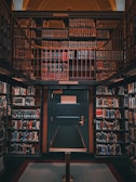 A richly wooden-paneled library alcove filled with shelves of colorful books. The scene is symmetrical, with a central green door labeled as Deck 46, indicating telephone books and city directories. The shelves surround the door, climbing up towards a mezzanine level, and are densely packed with books of various sizes and colors.
