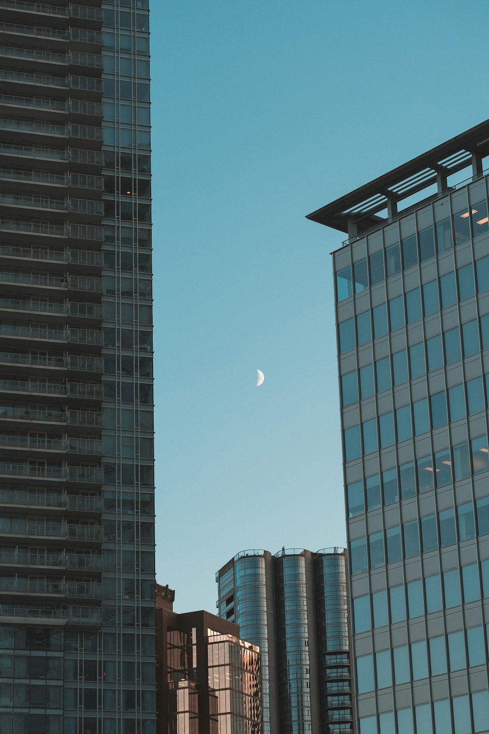 a moon in the sky between skyscrapers