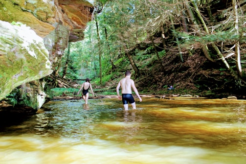 a man and woman walking in a river