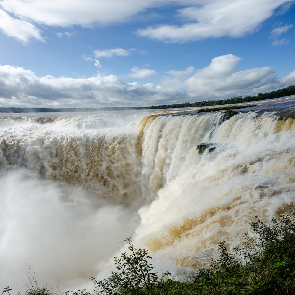 a waterfall with clouds in the sky