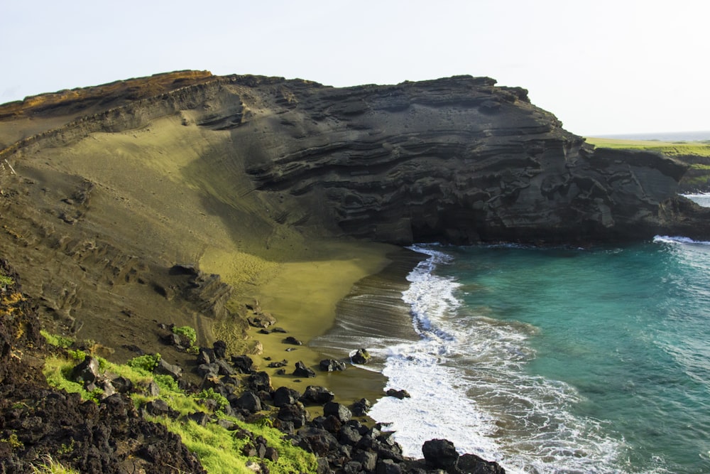 a rocky cliff next to a body of water