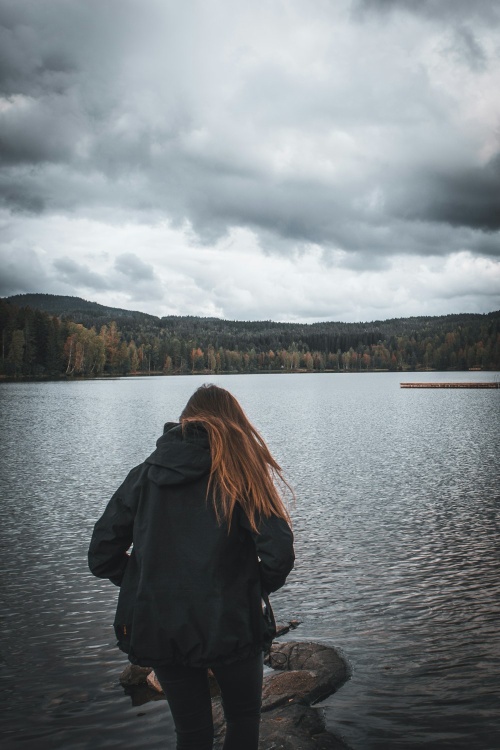 Eine Person, die auf einem Felsen steht und auf ein Gewässer schaut