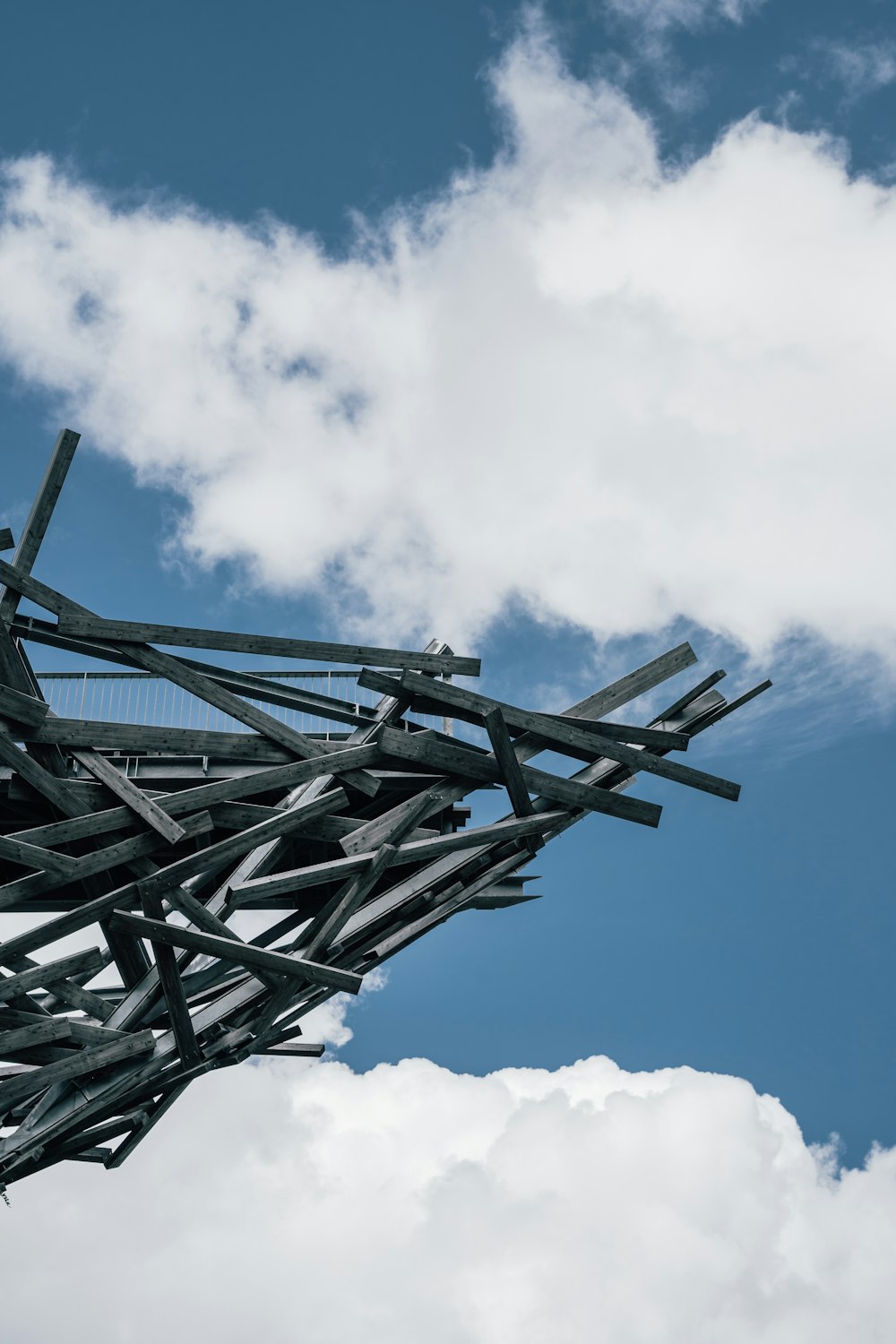 a large metal structure with clouds in the background