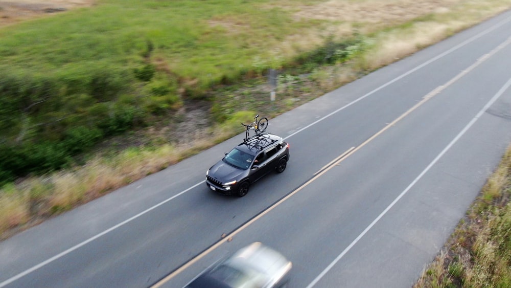 a car with a bike on the hood driving down a road