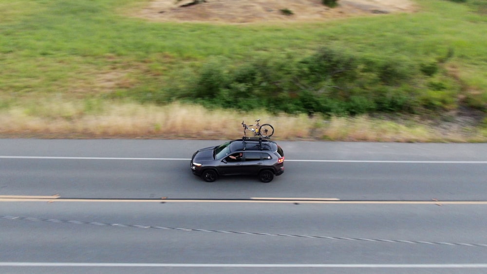 a car with bicycles on top of it driving down a road