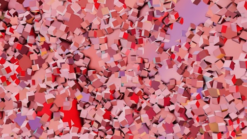 A chaotic and colorful pattern consisting of numerous small, three-dimensional cubes scattered across the canvas. Varying shades of red, pink, and purple dominate the scene, creating a vibrant and dynamic visual effect.