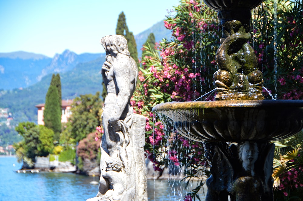 a statue of a person holding a torch in front of a body of water