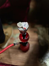 Close-up of a sleek black hookah with glowing coals and swirling smoke.