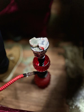Close-up of a sleek black hookah with glowing coals on top.