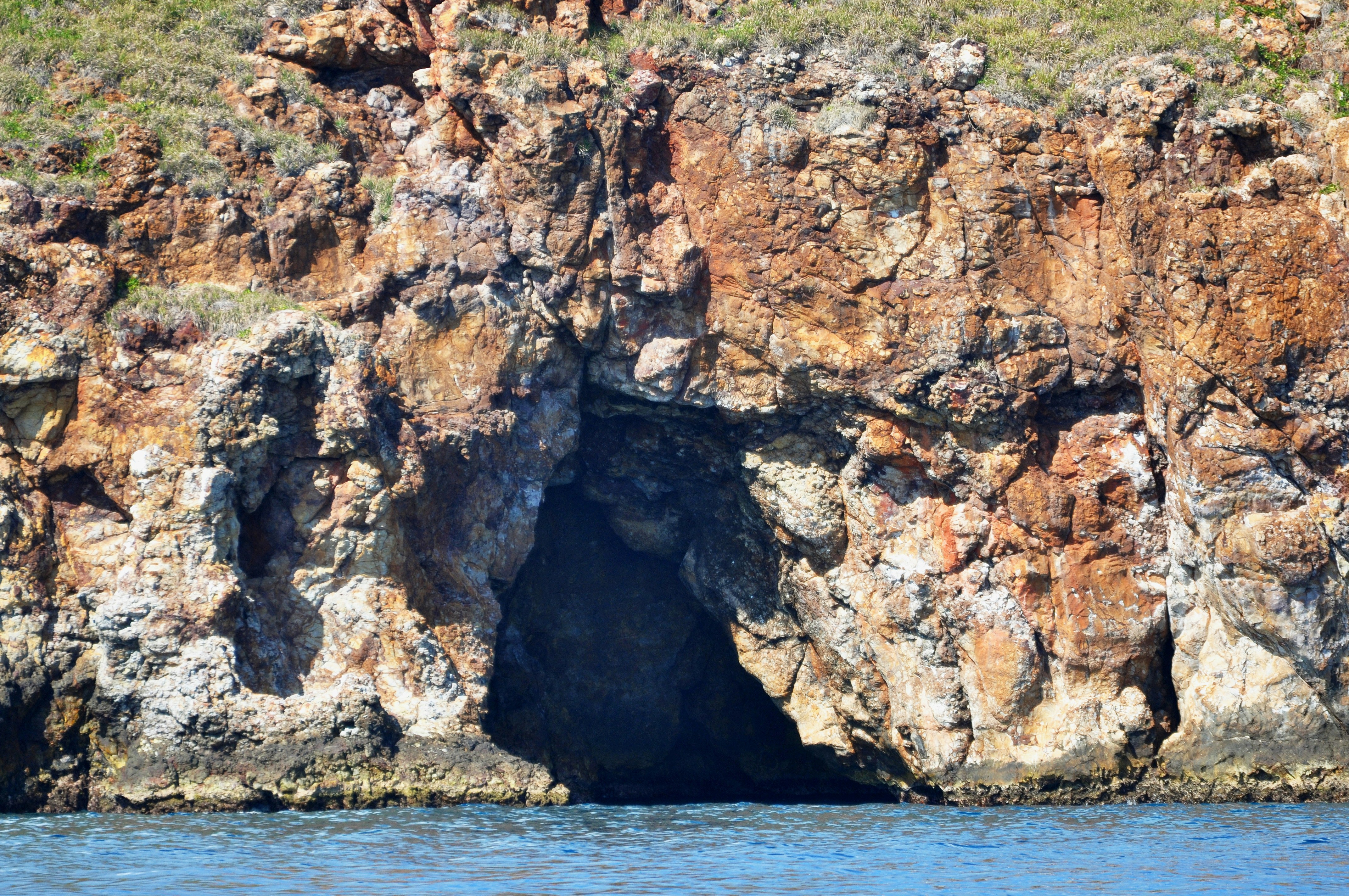 a cliff with a cave in it, A sea cave entrance on Saba Island.
