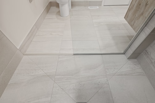 Wide shot of a spacious bathroom floor featuring a classic subway tile pattern with contrasting grout.