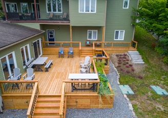 a deck with chairs and tables on it next to a house