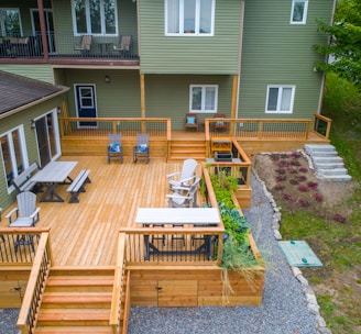 a deck with chairs and tables on it next to a house