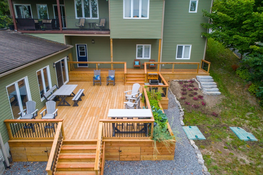 a deck with chairs and tables on it next to a house