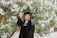 Portrait of a smiling alumnus in school uniform standing by the historic oak tree on campus.
