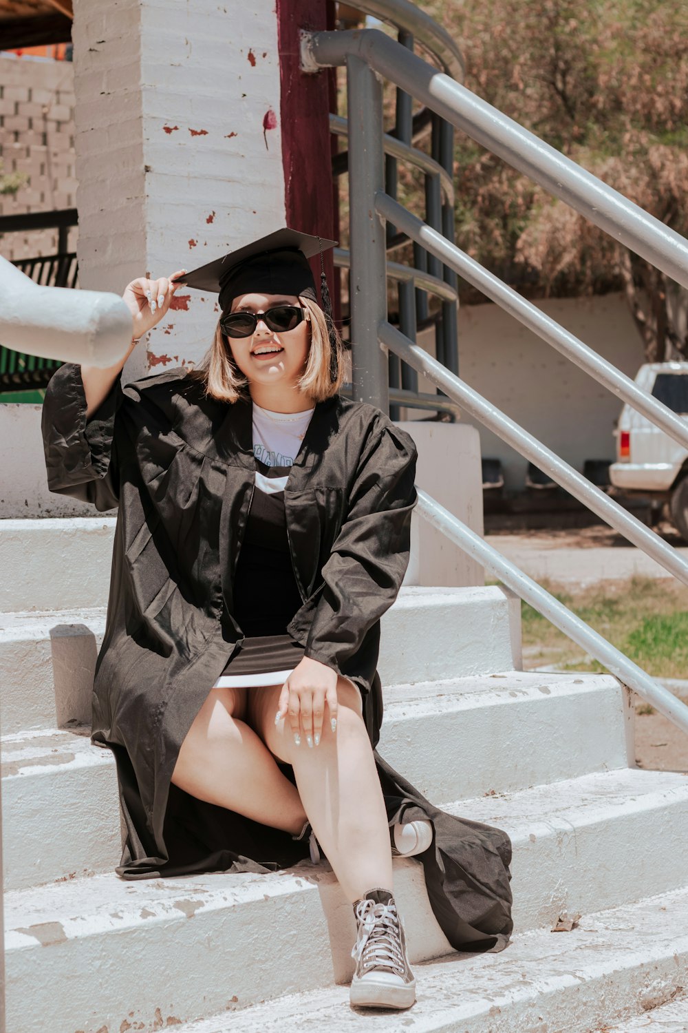 a person in a graduation cap and gown sitting on stairs