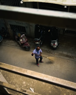 A clean street being swept by a modern street cleaning machine with clear skies above.