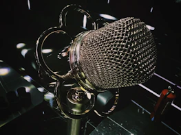 A sleek microphone icon styled like a medieval sword with golden highlights.