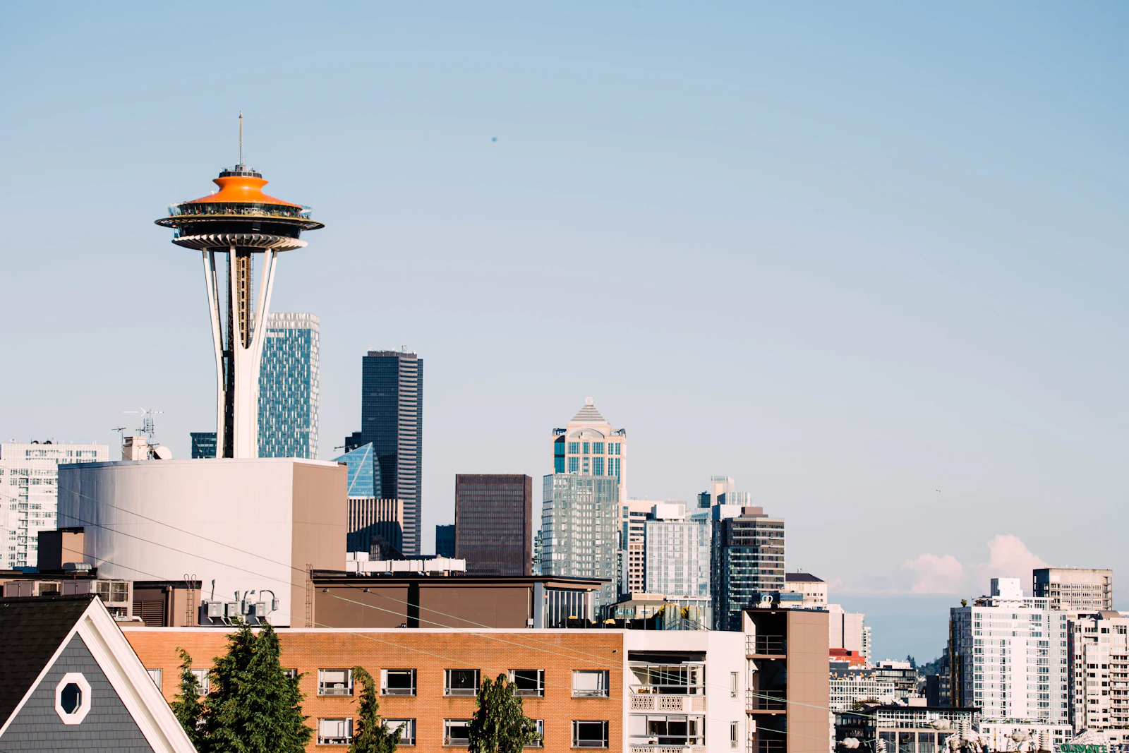 Space Needle rising above lower Queen Anne rooftops with downtown Seattle towers in the background