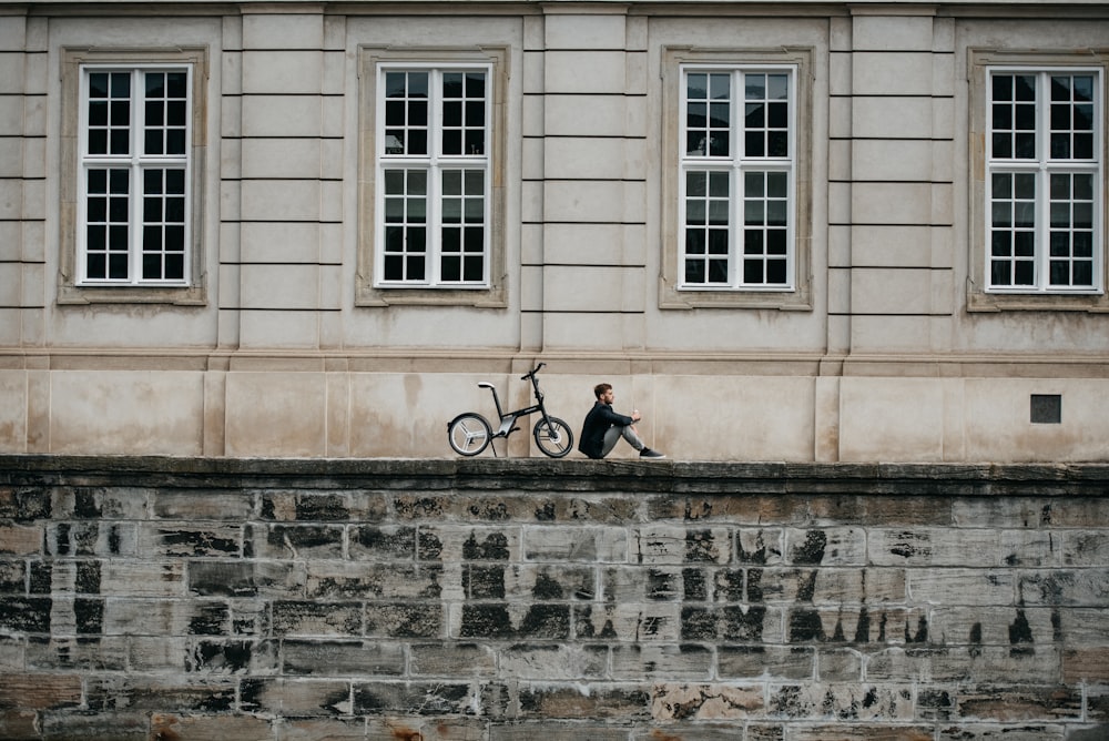 a person sitting on a wall next to a bicycle