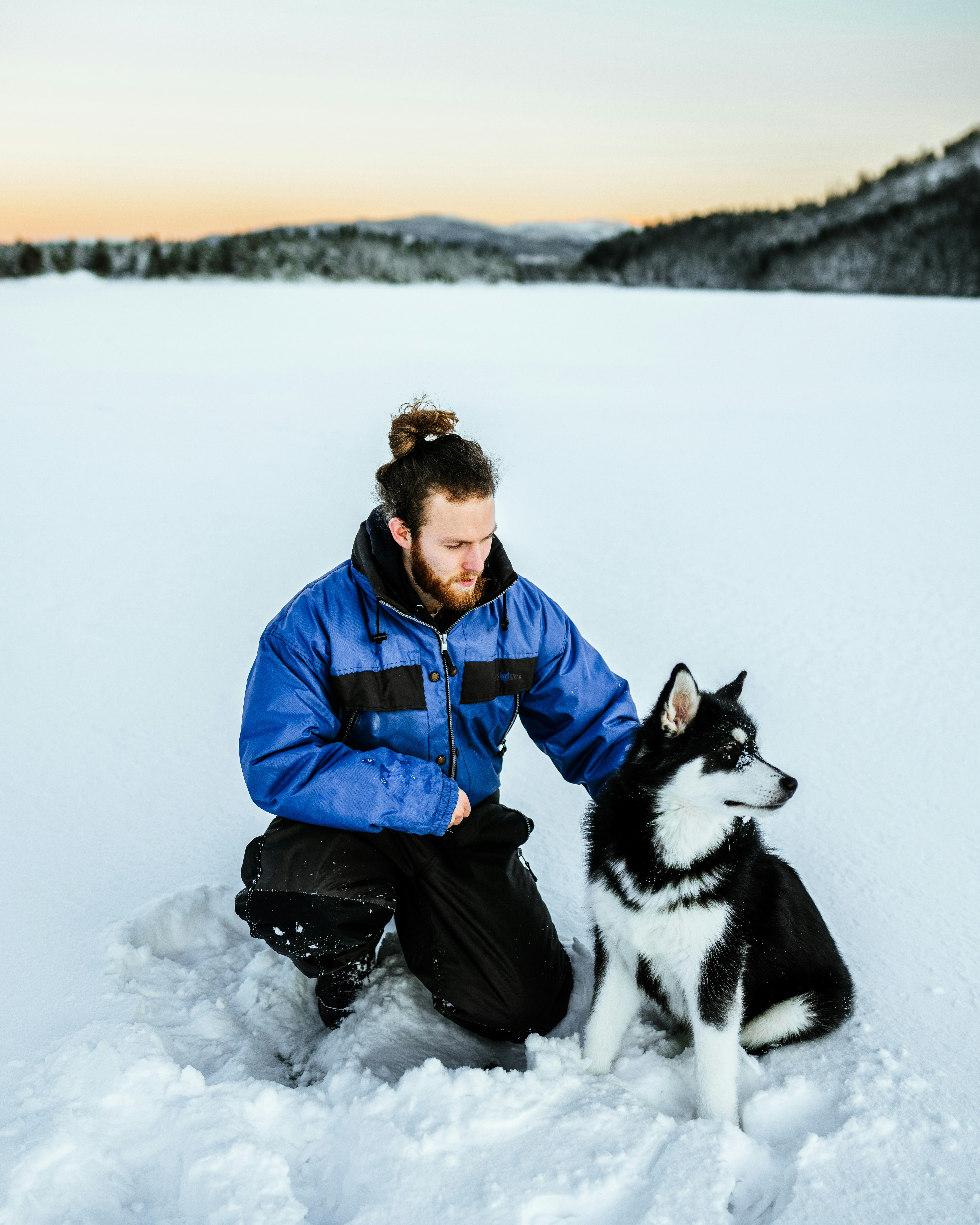 um homem ajoelhado na neve com um cão