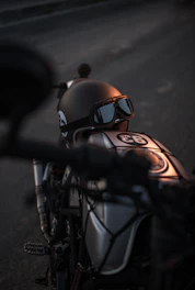 Close-up of a rugged motorcycle helmet resting on a vintage bike seat under soft natural light.