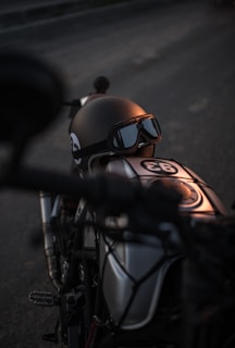 Close-up of a matte black helmet resting on a motorcycle seat under soft sunlight