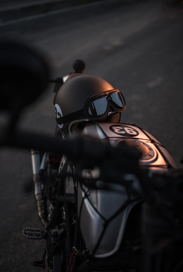 Close-up of a matte black Lumina helmet resting on a vintage motorcycle seat in urban sunlight.