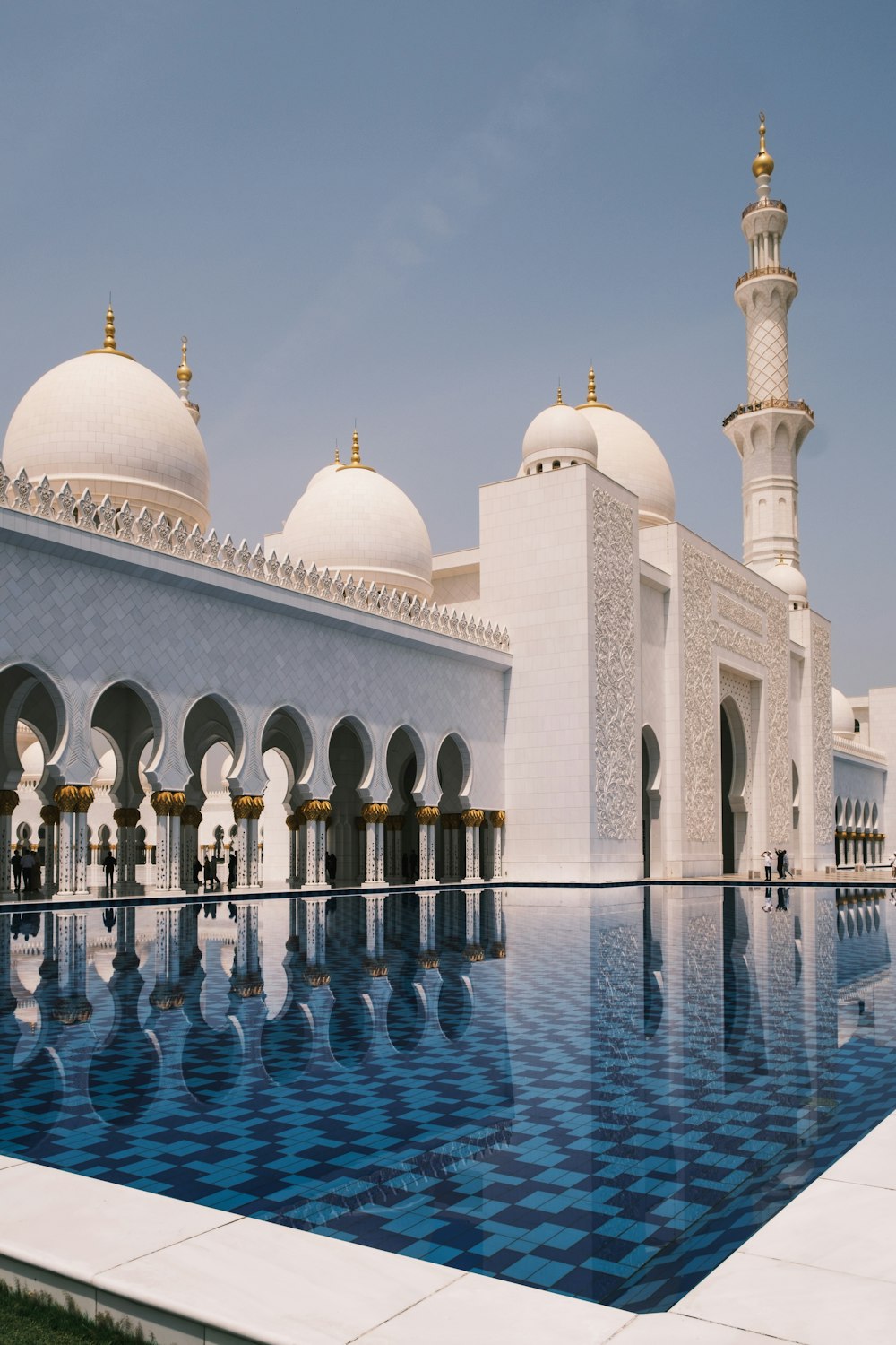 a large white building with domed roofs with Sheikh Zayed Mosque in the background