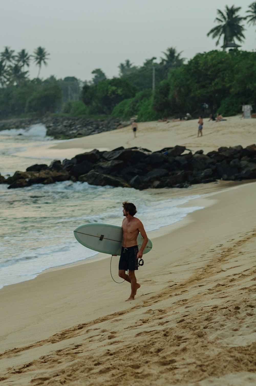 a person carrying a surfboard on a beach