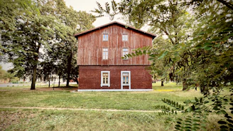 Front view of a cozy two-story house with wooden accents and a lush green garden.
