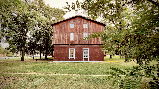 Front view of a cozy two-story house with wooden accents and a lush green garden.