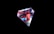 A multifaceted gem with a complex interplay of colors, featuring reflective surfaces that include shades of red, blue, and white. The gem is set against a stark black background, highlighting its vivid color spectrum and intricate geometric shape.