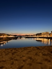 A serene view of Durgapur Barrage with calm waters reflecting the sky at sunset.