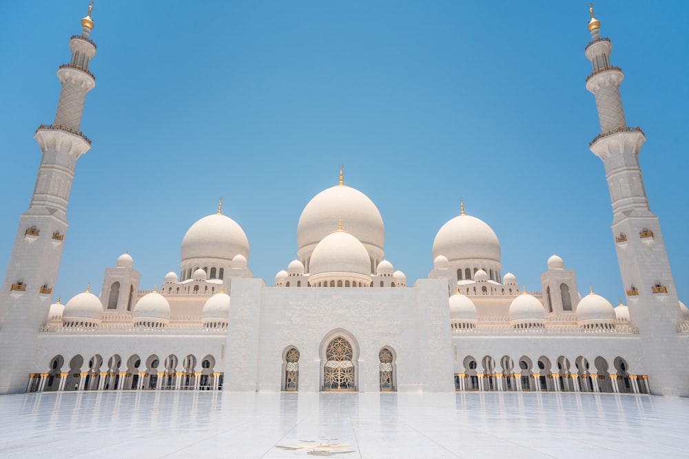 a large white building with towers with Sheikh Zayed Mosque in the background