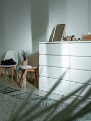 a white cabinet with a chair and a plant on top