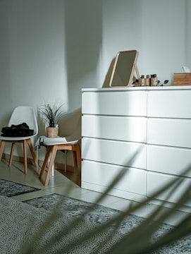 a white cabinet with a chair and a plant on top